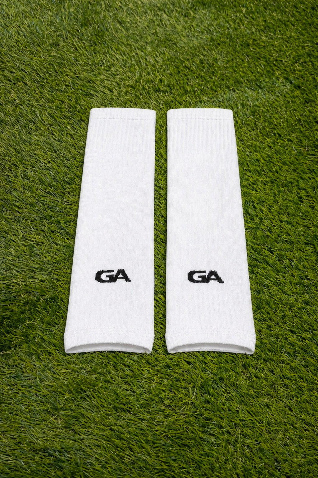 Paire de manchons blancs avec logo GA, posée sur le gazon