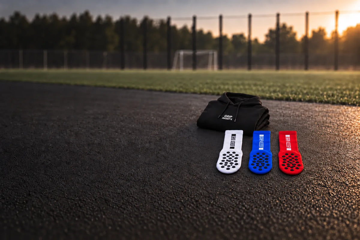 Hoodie noir et grip socks blanches, bleues et rouges Grip Assist X2 au bord d’un terrain