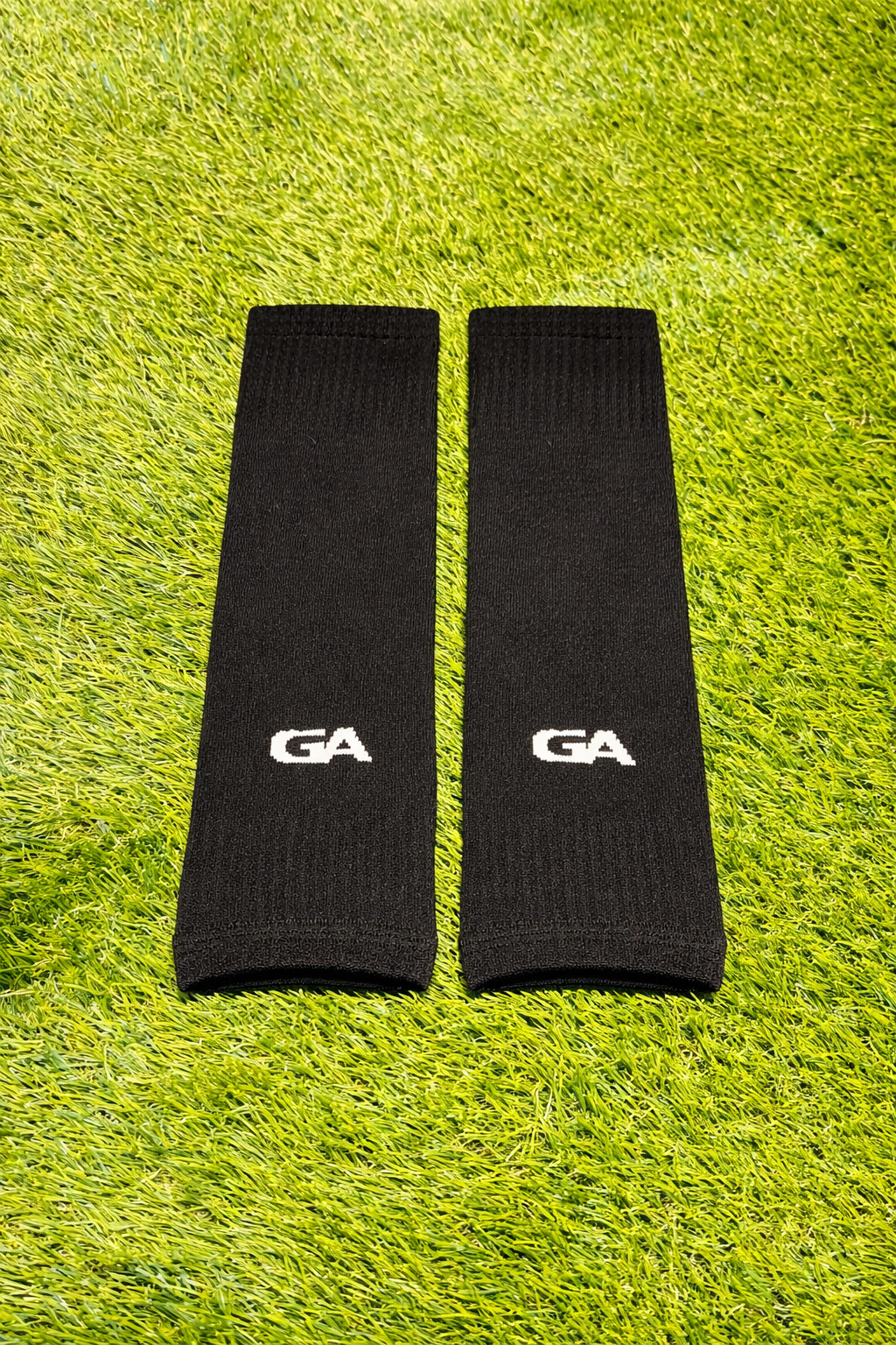 Paire de manchons noirs avec logo GA, posée sur le gazon