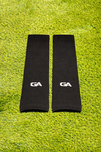Paire de manchons noirs avec logo GA, posée sur le gazon