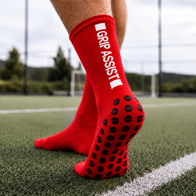 Grip socks rouges Grip Assist X2 à pastilles antidérapantes, sur un terrain synthétique