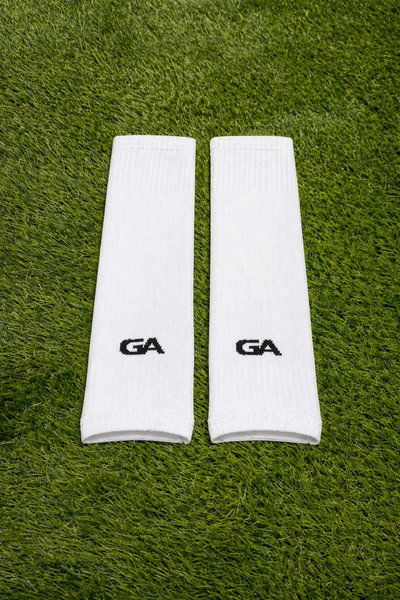Paire de manchons blancs avec logo GA, posée sur le gazon